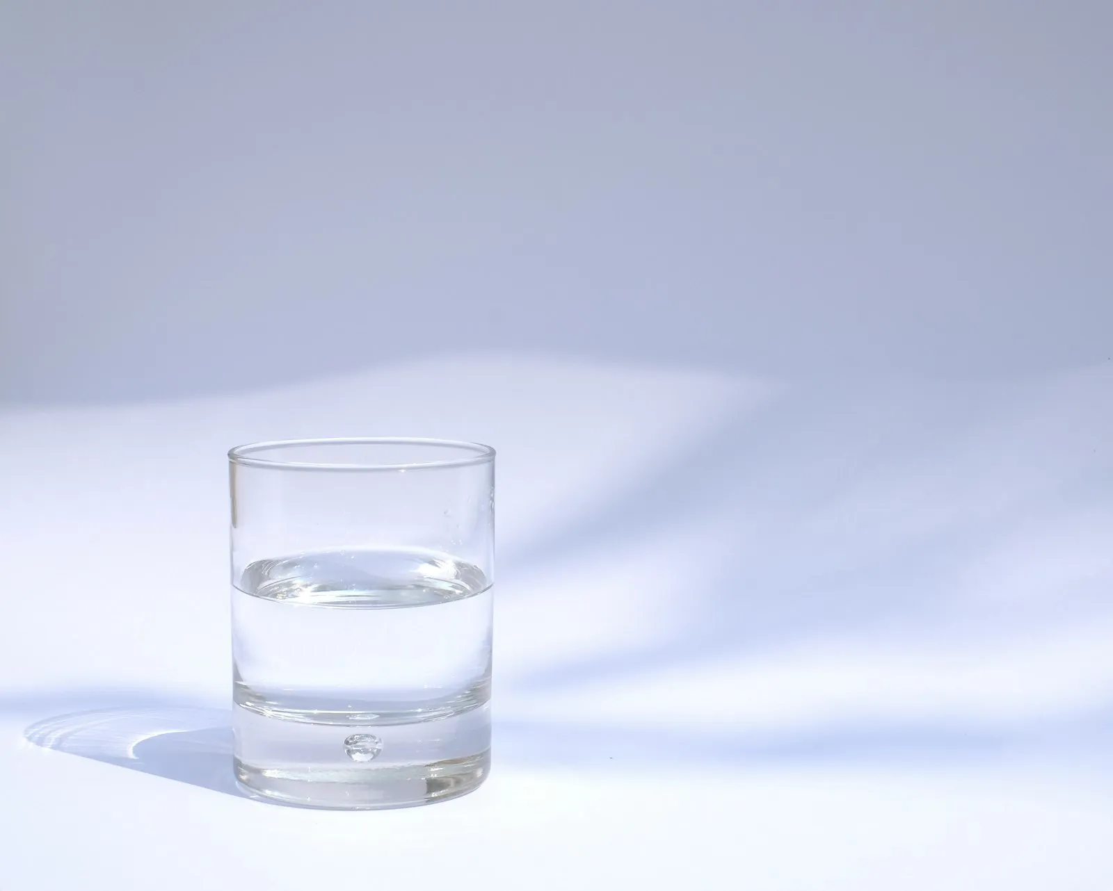 glass of water with pH test strip on kitchen table